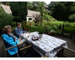 De eerste gasten genieten na de rondwandeling van de rust in de tuin.